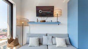 A modern living room with a grey sofa, a mounted television, and a blue accent wall.