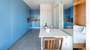 A modern kitchen with blue cabinets, a white countertop, and a wooden bench.