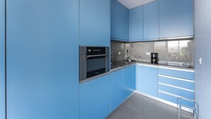 A modern kitchen with blue cabinets, a stainless steel oven, and a granite countertop.