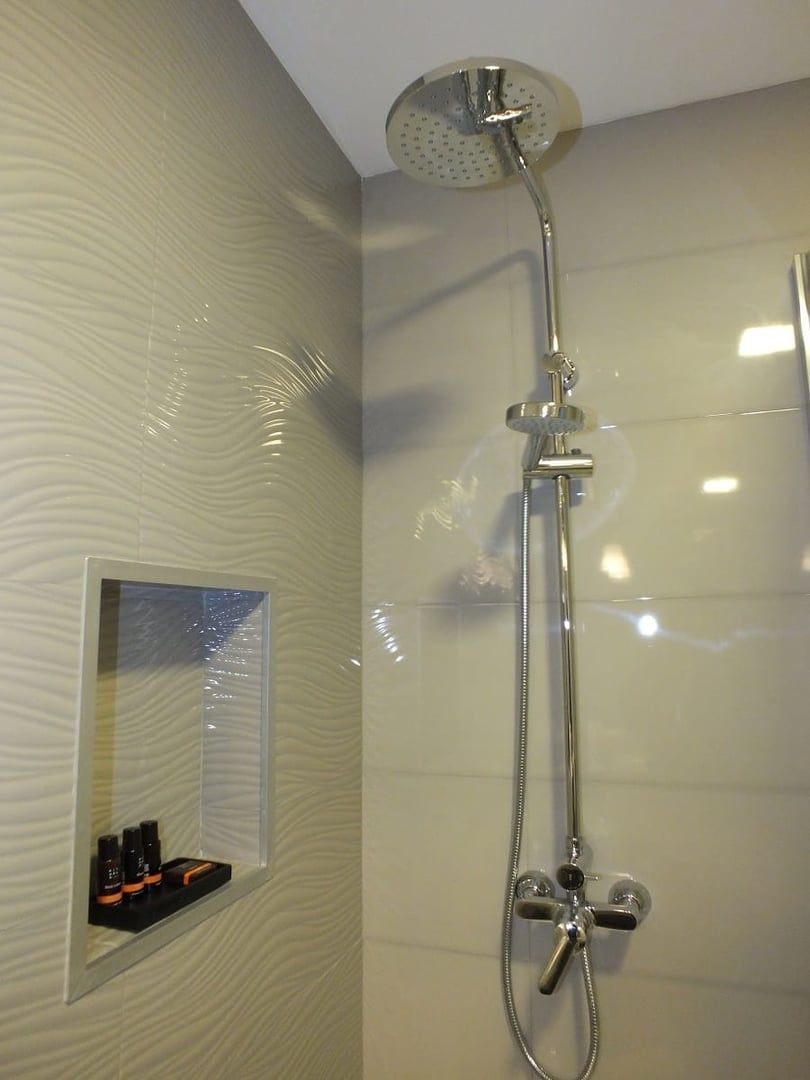 A shower with a handheld showerhead and a wall-mounted faucet.