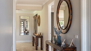 A hallway with a wooden console table, a large mirror, and a vase with flowers. - Bundjil Beach House I Walk to beach (Bass Coast)