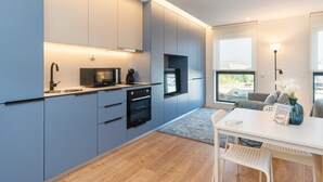A modern kitchen with grey cabinets, a built-in microwave, and an oven. There is a dining table with chairs and a vase with flowers. - GuestReady - A peaceful city refuge (Porto)
