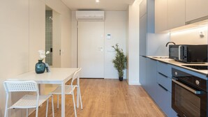 A modern kitchen with a white table, chairs, and a potted plant. - GuestReady - A peaceful city refuge (Porto)