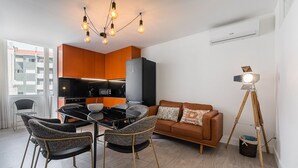 Uma sala de estar moderna com área de jantar, cozinha compacta e uma janela grande.