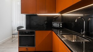 Uma cozinha moderna com bancada preta, pia de aço inoxidável e forno embutido.