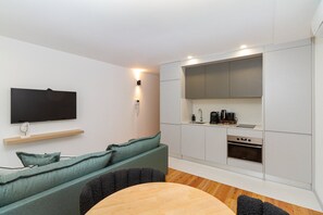 Cozy living space with a flat-screen TV, kitchen, and seating area.