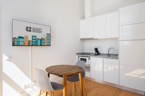 Eine moderne Küche mit weißen Schränken, einem Holzespeisetisch und zwei Stühlen. Ein Schild mit der Aufschrift 'GUEST READY' ist an der Wand angebracht.
