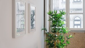 A room with a large window, a potted plant, and three framed artworks on the wall. - GuestReady - RNB Code Violet (Porto)