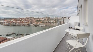 Un balcón con una mesa y sillas que da a un puerto con barcos y el skyline de la ciudad.