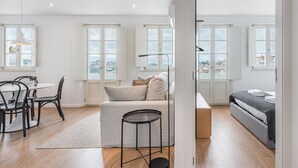 Un apartamento moderno con comedor, sofá, cama y grandes ventanales con vistas a la ciudad.