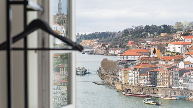 Vista de un río con barcos, edificios históricos y una torre destacada.