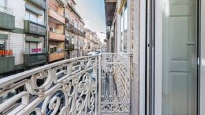 A narrow street with buildings on either side, featuring balconies with metal railings and a sign that reads "CRECHE". - GuestReady - Comendador Sto Ildefonso III (Porto)