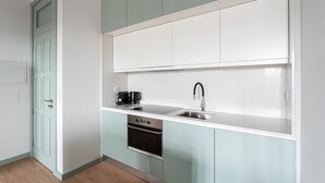 A compact kitchen with a built-in oven, a coffee maker, and a sink. - GuestReady - A brilliant stay near Ribeira (Porto)