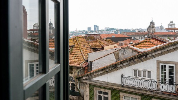 A view of rooftops with red tiles and a cityscape in the background. - GuestReady - A brilliant stay near Ribeira (Porto)