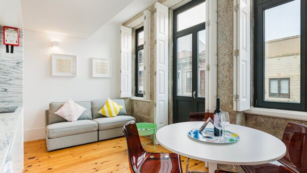 Un salon moderne avec un canapé gris, une table de salle à manger ronde et un fauteuil vert.