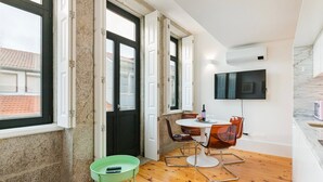 Une cuisine moderne équipée d’un téléviseur, dotée d’un plancher en bois et comprenant un coin repas avec une table et des chaises.