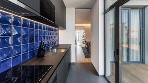 A modern kitchen with blue tiles, a built-in oven, and a sliding glass door leading to a balcony.