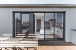 A modern balcony with a wooden table and chairs, a white sofa, and a glass door leading to an indoor space. - GuestReady - Mompilher Apartments (Porto)