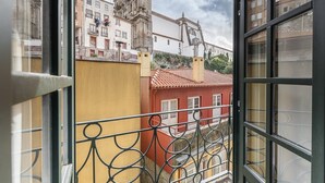 En balkon med jerngitterudsigt over en by med historiske bygninger og en kirke.