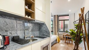 Une cuisine compacte dotée d’un plan de travail en marbre, d’un four encastré et d’un grille-pain.