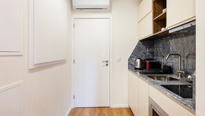 Une cuisine compacte avec une porte blanche, un four encastré, un évier et un plan de travail en marbre.