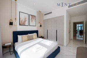 Quarto moderno com uma cama grande, mesas de cabeceira, guarda-roupa e uma obra de arte emoldurada na parede.