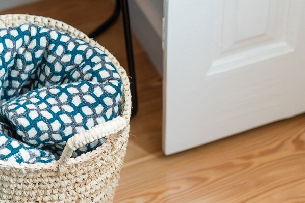 A woven basket with a blue and white patterned cushion. - GuestReady - Chakra Duplex (Porto)