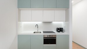 A compact kitchen with a sink, a coffee maker, and an oven. - GuestReady - A modern stay in Downtown (Porto)