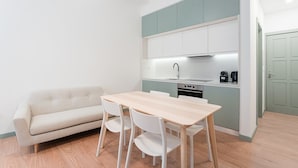 A compact kitchen with a dining table and chairs, a sofa, and a coffee machine. - GuestReady - A modern stay in Downtown (Porto)