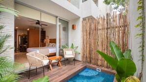 A modern hotel room with a balcony, a small pool, and a dining area with wicker furniture. - NHOA 108B Lux 1BR Condo Plunge Pool in Aldea Zama (Tulum)