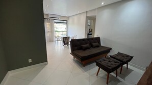 A modern living room with a sofa, ottoman, and dining table. - LIBERTY PLACE - PARQUE DAS ROSAS (Rio de Janeiro)