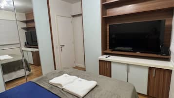 Un dormitorio con cama, televisión, espejo y armario.
