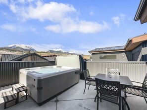 A hot tub on a patio with a mountain view, a table and chairs, and a wooden fence. - 541 Center Circle 3br 3.5ba 3 Bedroom Townhouse by RedAwning (Silverthorne)
