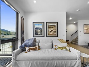 A modern living room with a large window, a sofa with decorative pillows, and two framed pictures on the wall. - 541 Center Circle 3br 3.5ba 3 Bedroom Townhouse by RedAwning (Silverthorne)