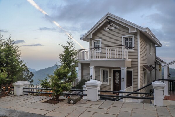 A two-story house with a balcony, a front door, and a staircase leading to the entrance. - Eagles Wings Abode (Coonoor)