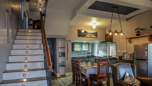 A modern kitchen with a dining area, wooden staircase, and a chandelier. - Eagles Wings Abode (Coonoor)
