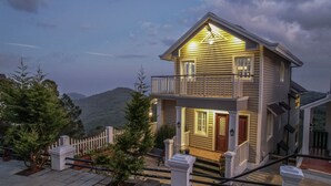 A two-story house with a balcony, a front door, and a staircase leading to the entrance. - Eagles Wings Abode (Coonoor)