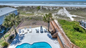 Uma área de piscina com espreguiçadeiras e vista para o oceano.