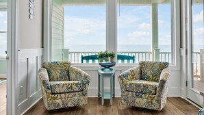 Ein Zimmer mit zwei blumigen Sesseln, die einen Balkon mit Meerblick bieten.