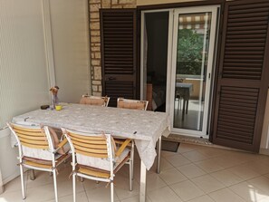 A dining area with a table set for four, surrounded by wooden chairs with cushioned seats.