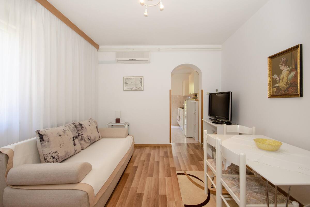 Uma sala de estar moderna com sofá, mesa de jantar e televisão.