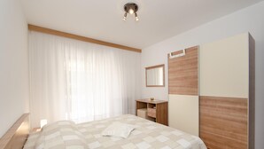 A bedroom with a bed, a bedside table, a mirror, and a wardrobe. - Apartments Bungavilia (Rovinj)
