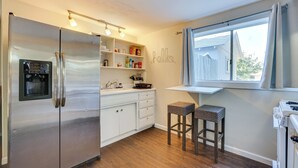 A kitchen with a stainless steel refrigerator, white cabinets, wooden flooring, a window with a view, and a 'hello' wall decoration. - 5 Mi to Dtwn: Pet-friendly Phoenix Studio w/ Yard (Phoenix)