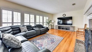 A living room with a sectional sofa, a flat-screen TV, a fireplace, and large windows. - Jacksonville Vacation Home w/ Trout River Access (Jacksonville)