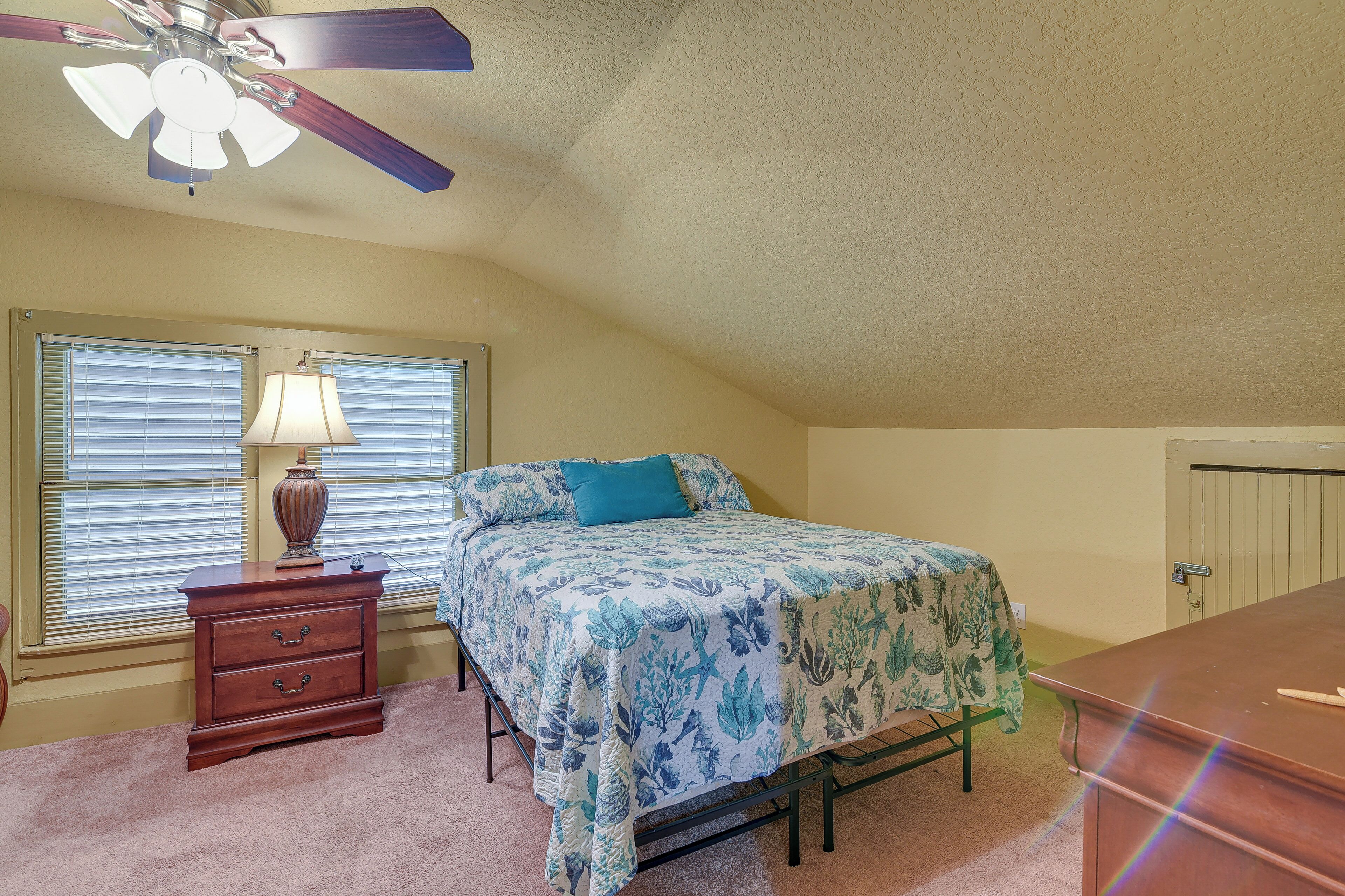 A bedroom with a bed, a nightstand, a lamp, and a ceiling fan.