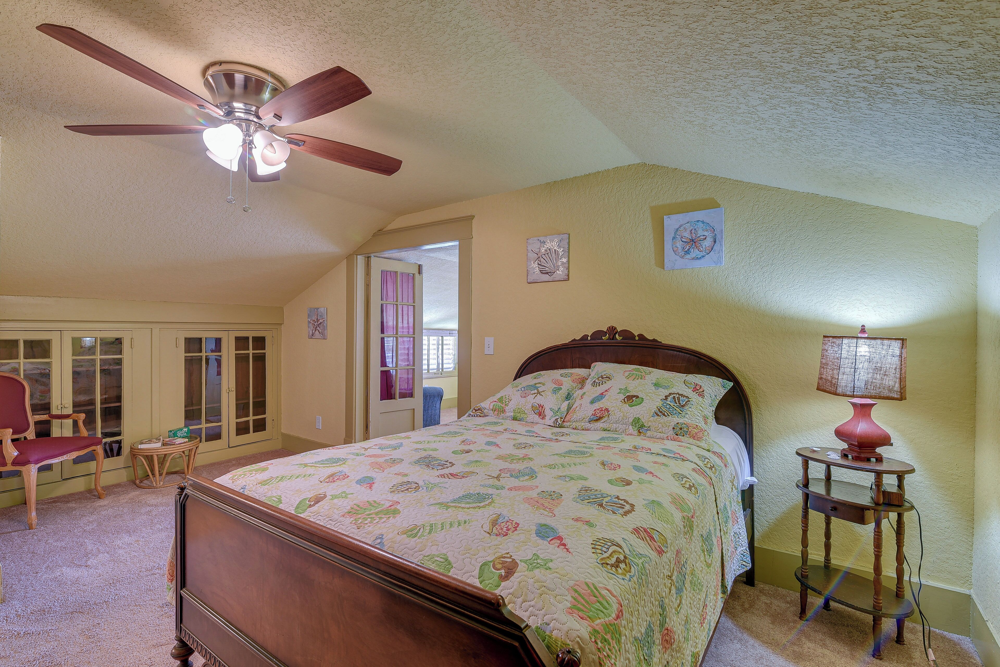 Une chambre à coucher avec un lit, un ventilateur de plafond, une lampe et une chaise.