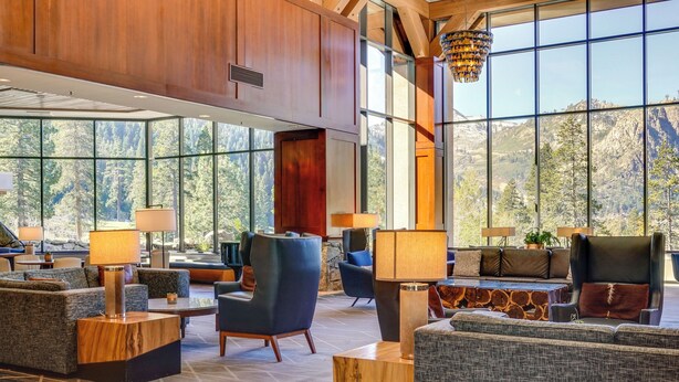 En rymlig lobby med stora fönster som erbjuder utsikt över bergen, modern möblering och en stor kristallkrona.