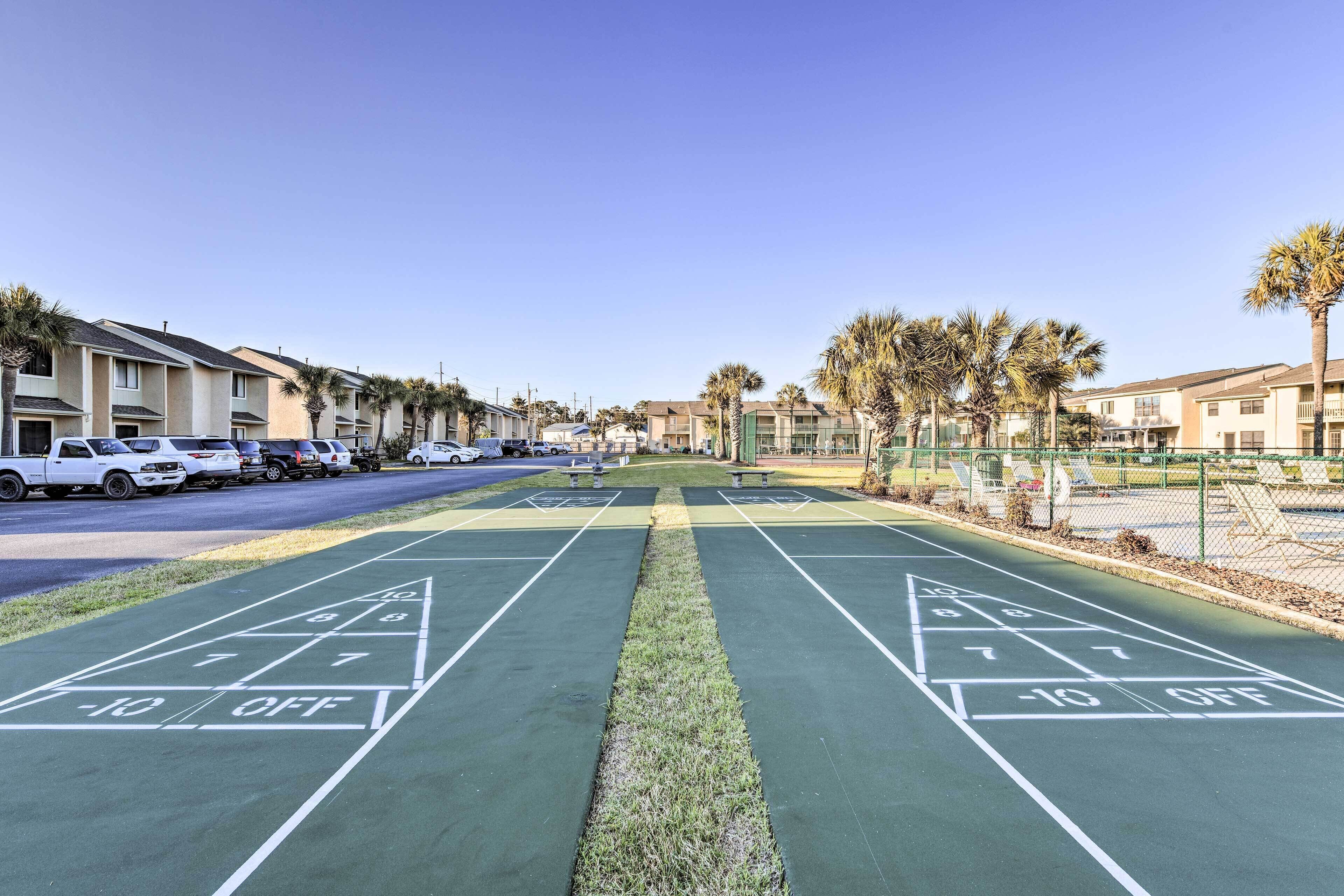 Ein Shuffleboard-Spielfeld mit deutlich markiertem Spielfluss, umgeben von parkenden Autos und Wohnhäusern.