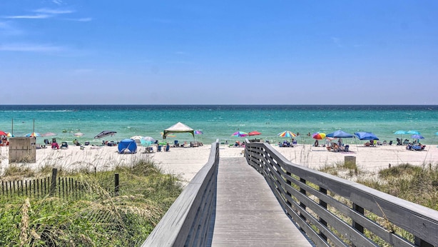 A wooden boardwalk leading to a beach with umbrellas and beach chairs. - Walk to Beach + Restaurants: PCB Resort Condo! (Panama City Beach)