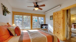 A bedroom with a large bed, a ceiling fan, a television, and a view of the outdoors through large windows. - 1/2 Mi to Granby Ranch: Townhome w/ Fireplace! (Granby)